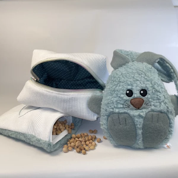 Geschenkeset zur Geburt mit Kuscheltier, Kirschkernkissen und praktischer Stofftasche. Auf der Abbildung ist das Kirschkernkissen geöffnet und die Kirschkerne sind zu sehen