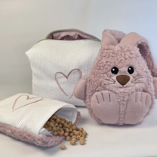 Geschenkeset zur Taufe mit Kuscheltier, Kirschkernkissen und praktischer Stofftasche. Auf der Abbildung ist das Kirschkernkissen geöffnet und die Kirschkerne sind zu sehen